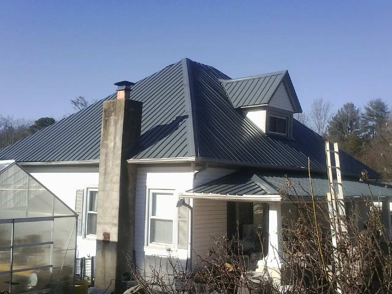 Dark blue standing seam metal roof on a white farmhouse with dormer — Slate & Tile Roof Repair by Roofing Brothers in Onset