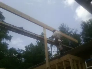 Carpenter setting a ridge beam over a new addition frame — Ice Dam Removal by Roofing Brothers in Onset