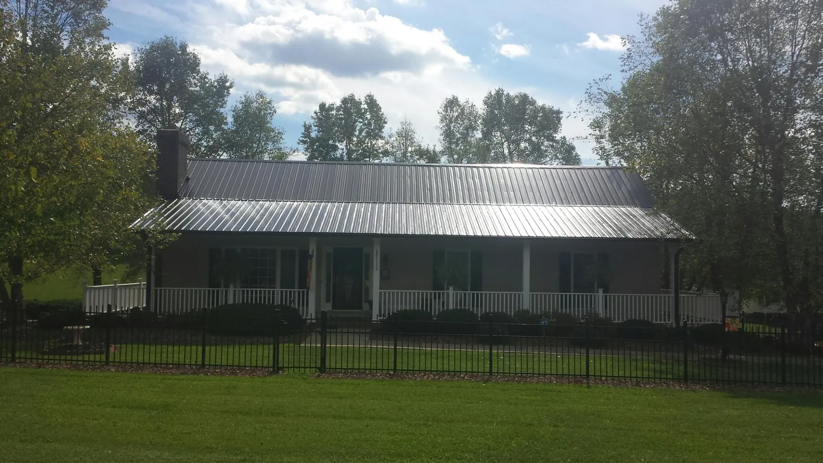 Gray metal roof on a brick ranch with a full width front porch — Gutter Guard Installation work by our crew in Onset