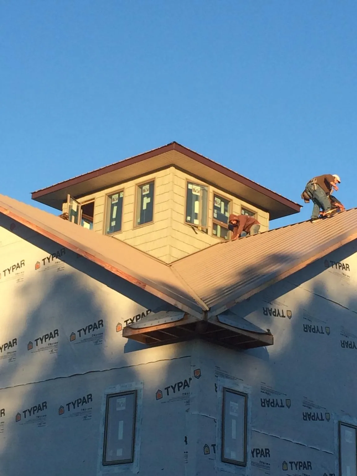 Roofers working around a rooftop cupola on a new metal roof at sunset — Roof Waterproofing in Onset by Roofing Brothers